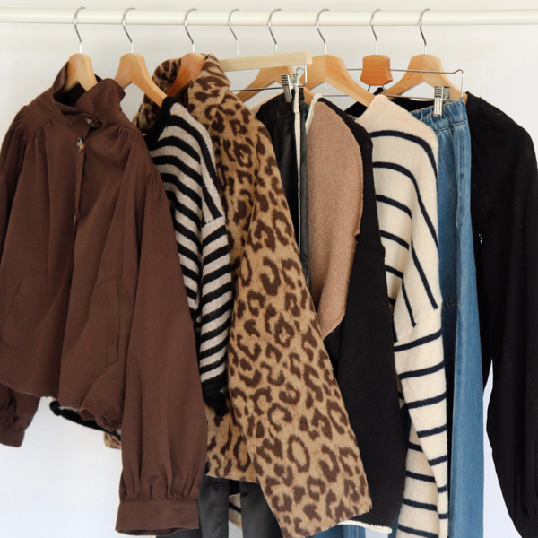 a rack of clothing with various jackets, tops and cardigans