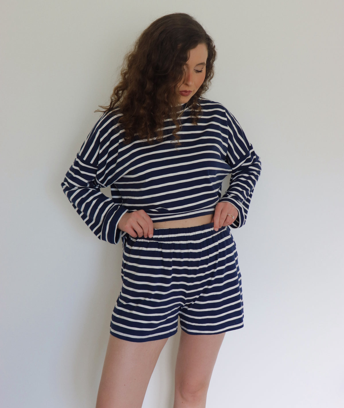 Woman wearing a navy and white striped outfit against a plain background