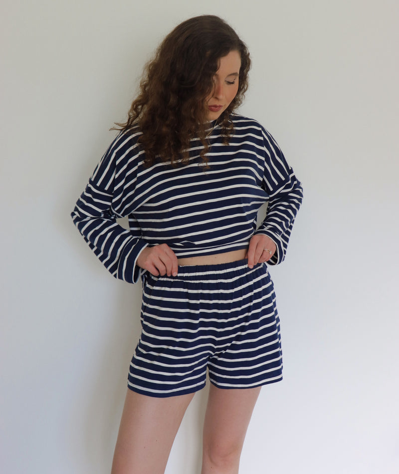 Woman wearing a navy and white striped outfit against a plain background