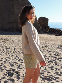 Woman standing on a beach with large rocks and ocean in the background