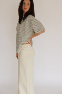 Woman wearing a striped shirt and cream wide-leg pants against a plain background