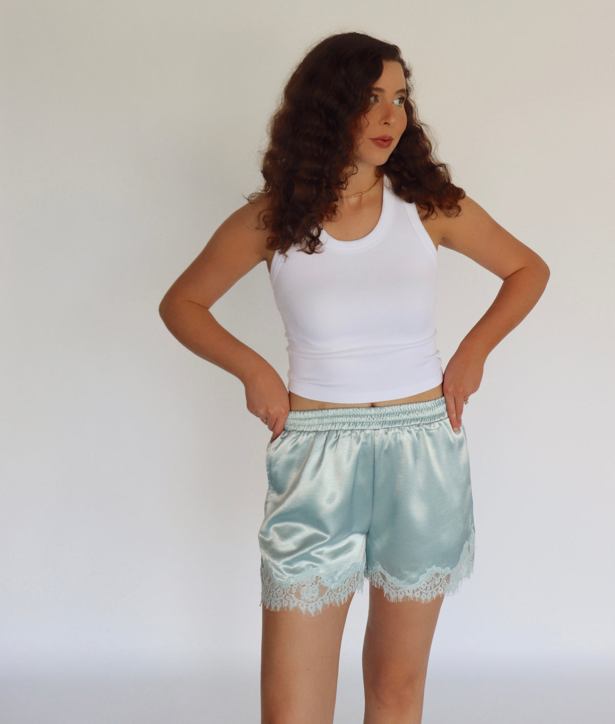 woman wearing mint blue colored shorts and a white tank top