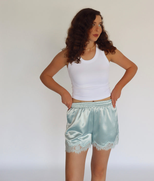 woman wearing mint blue colored shorts and a white tank top