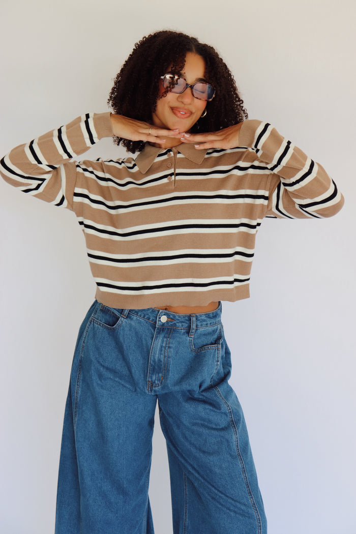 Person wearing a striped shirt and blue jeans against a white background