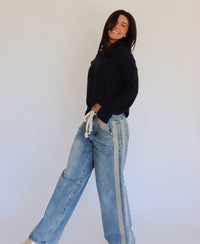 Woman wearing a blue top and blue jeans against a white background