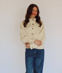 Woman wearing a beige jacket with buttons against a plain background