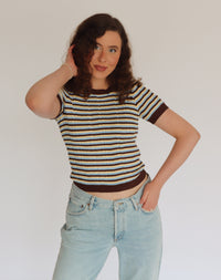Woman wearing a striped shirt and jeans against a plain background