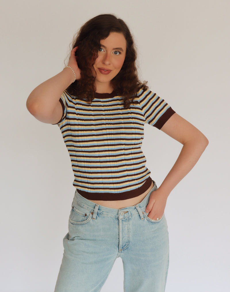 Woman wearing a striped shirt and jeans against a plain background