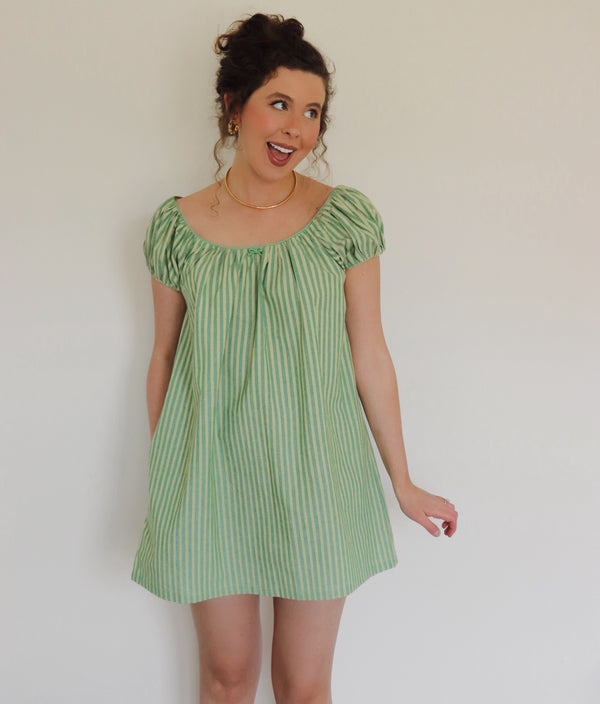 Woman wearing striped green dress against a white wall