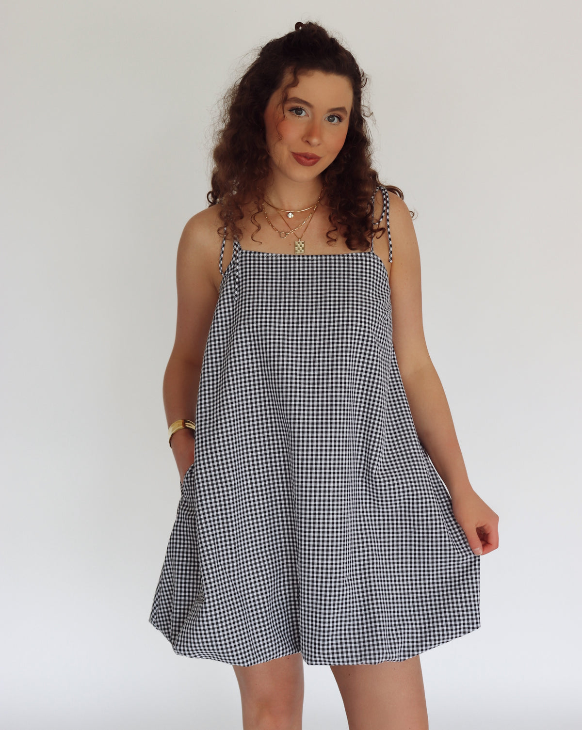 Woman wearing a black and white checkered dress against a plain background