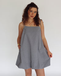 Woman wearing a black and white checkered dress against a plain background