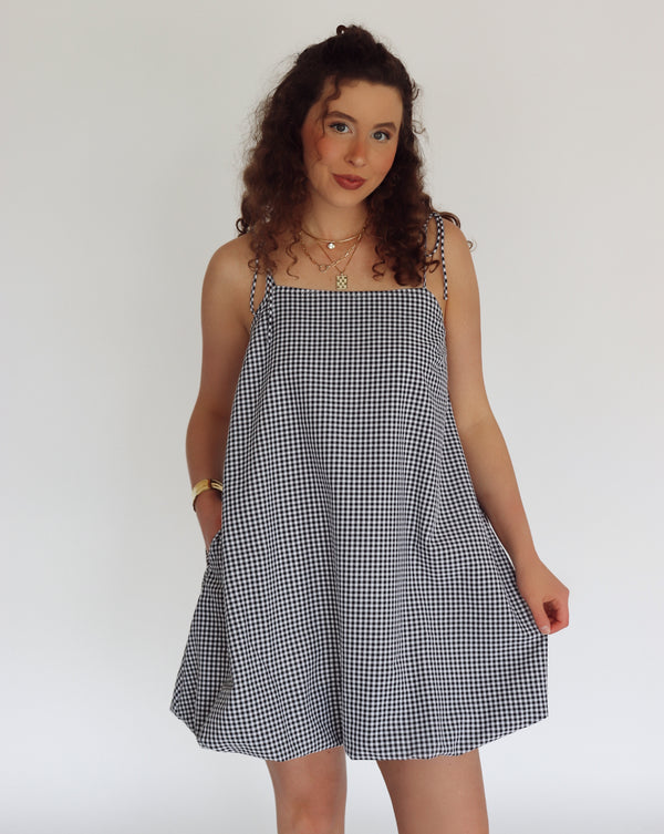 Woman wearing a black and white checkered dress against a plain background