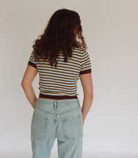 Woman wearing a striped shirt and jeans against a plain background