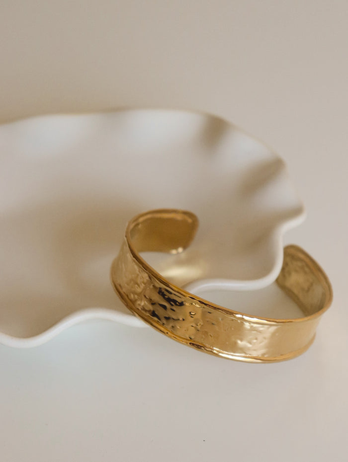Gold bracelet on a white ceramic dish