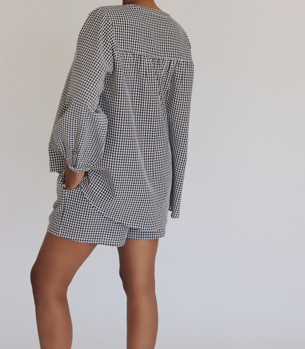 Person wearing a black and white checkered set  against a plain background