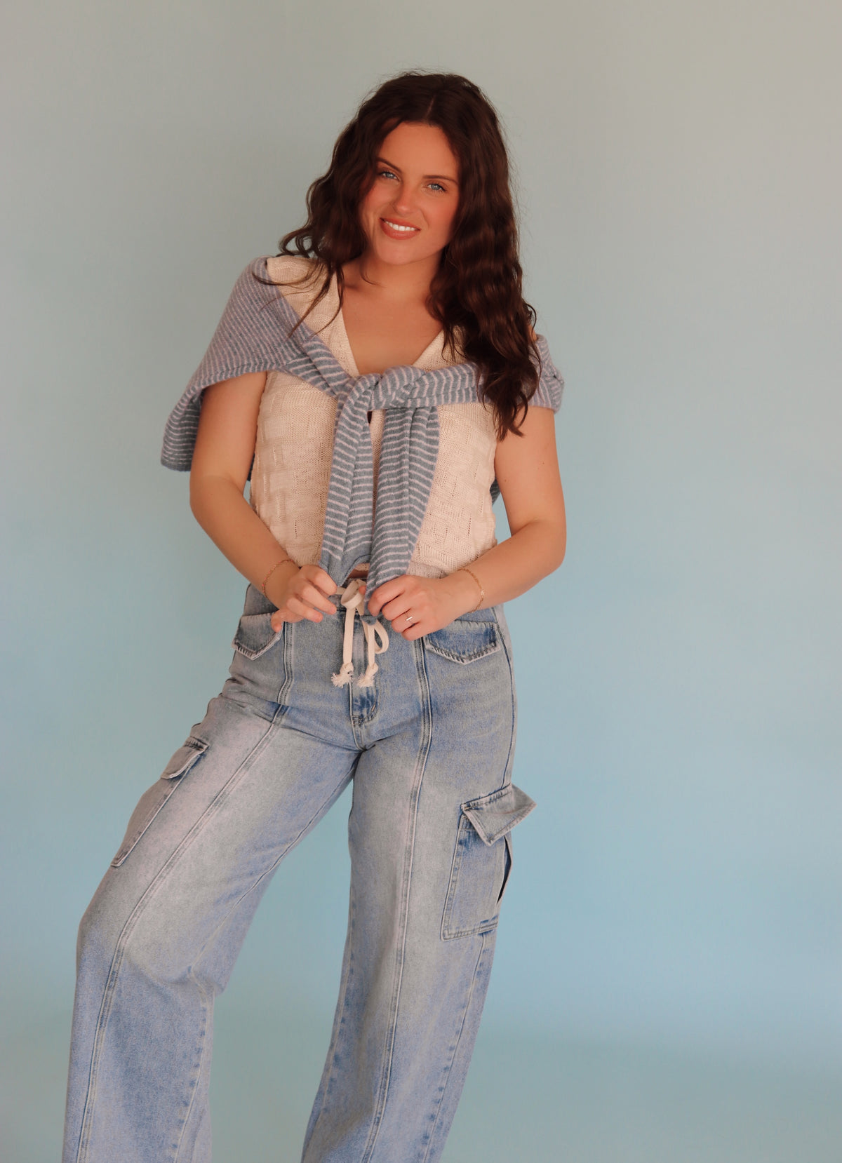 Woman wearing a vest and jeans against a plain background