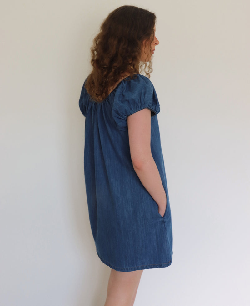 Woman wearing a blue denim dress against a plain background