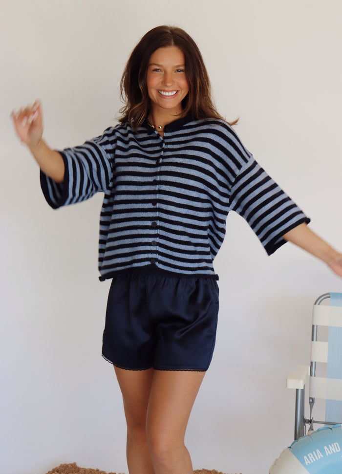 Woman wearing a navy and lighter blue striped shirt and navy shorts