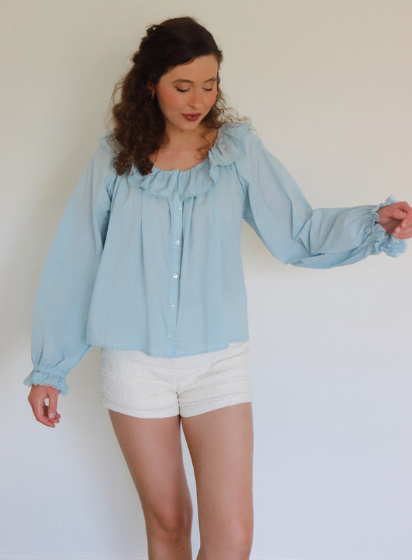 Woman wearing a light blue ruffled collar top and white shorts