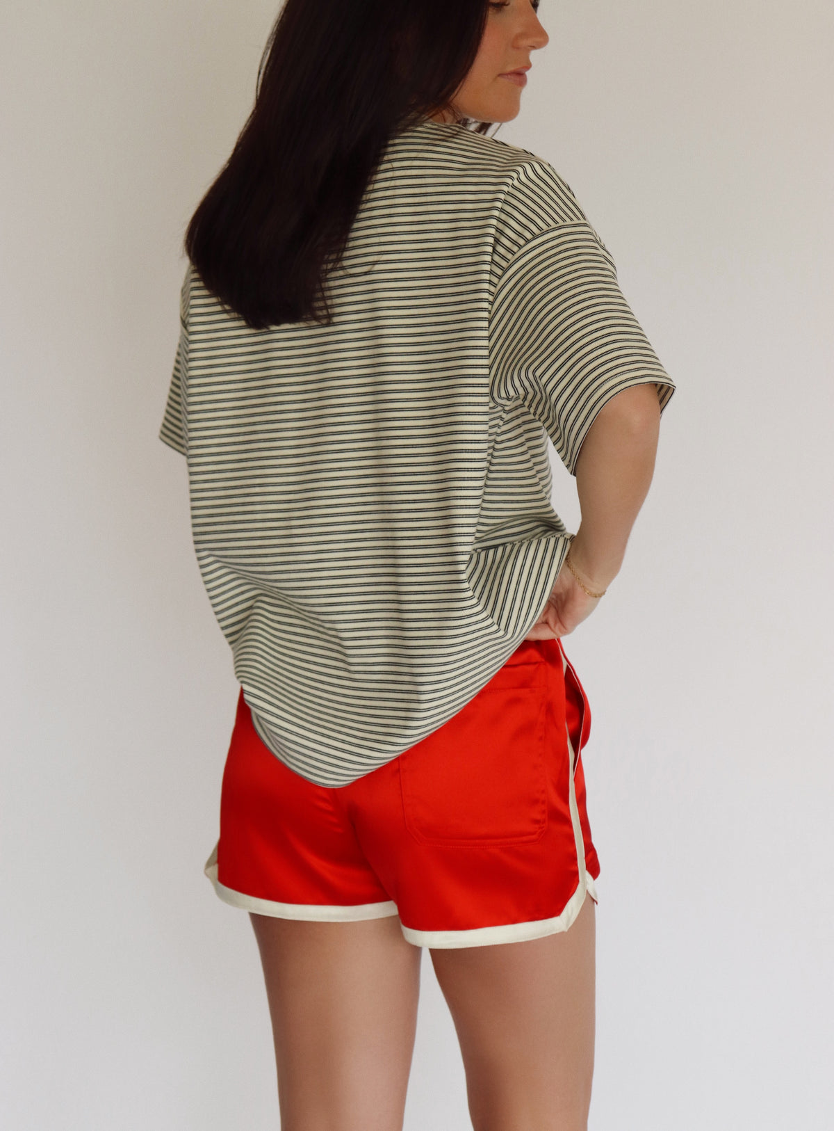 Person wearing a striped shirt and red shorts against a plain background
