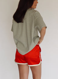 Person wearing a striped shirt and red shorts against a plain background