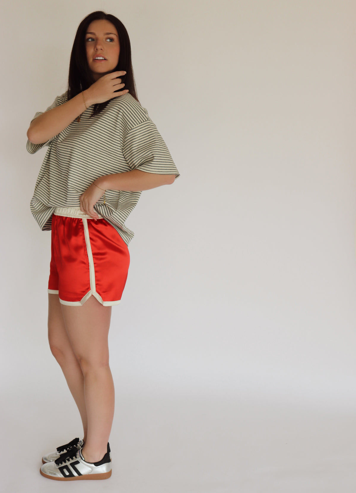 Woman wearing a striped shirt and  red shorts against a plain background