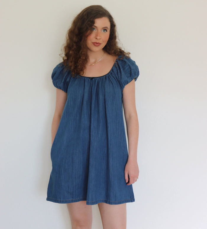 Woman wearing a blue denim dress against a plain background