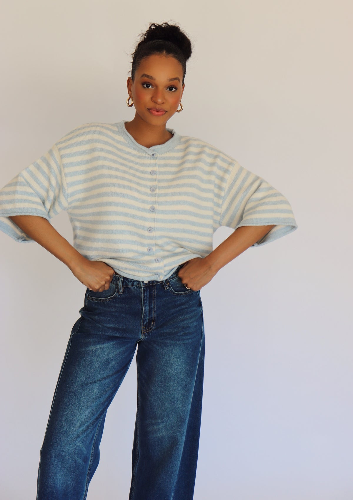 Woman wearing a striped cardigan and jeans against a plain background