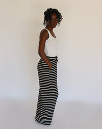 Woman wearing a white tank top and black and white striped pants on a white background