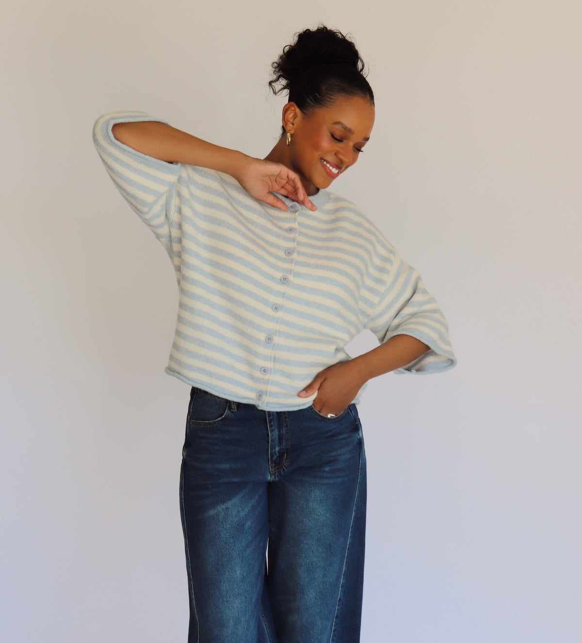 Woman wearing a striped cardigan and jeans against a plain background