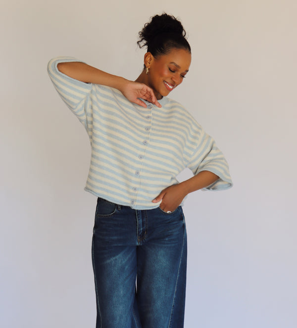 Woman wearing a striped cardigan and jeans against a plain background