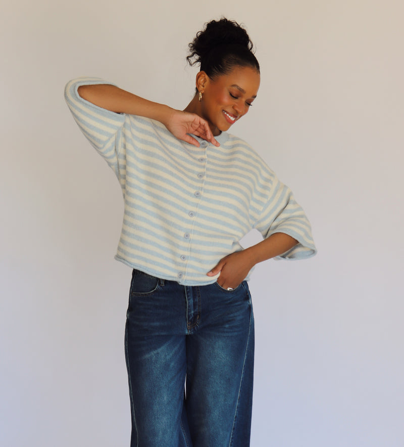 Woman wearing a striped cardigan and jeans against a plain background