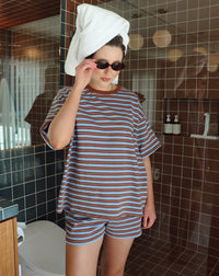 Person wearing a striped outfit with a towel on their head in a bathroom.