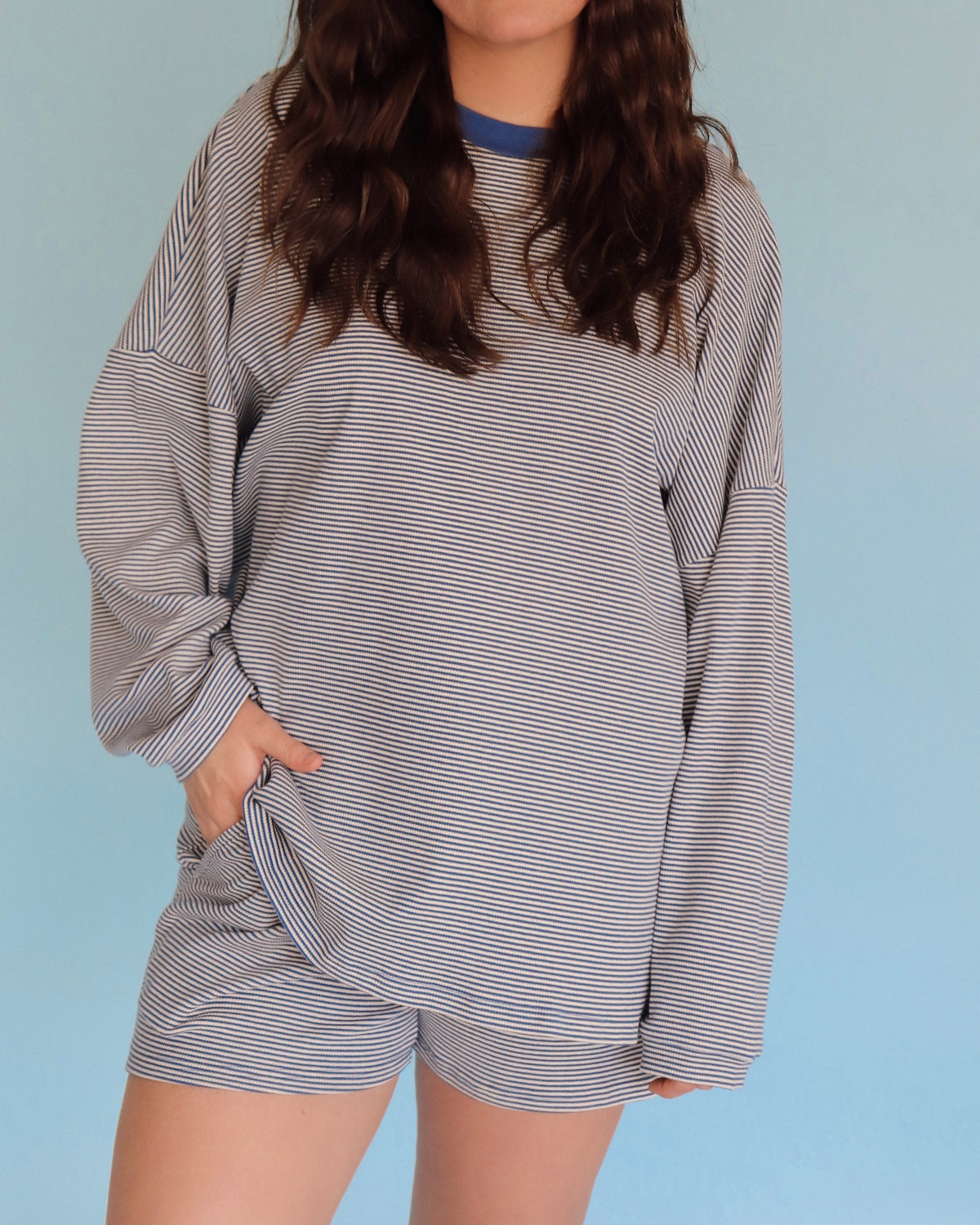 Person wearing a blue striped loungewear set against a light blue background