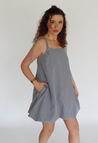 Woman wearing a black and white checkered dress against a plain background