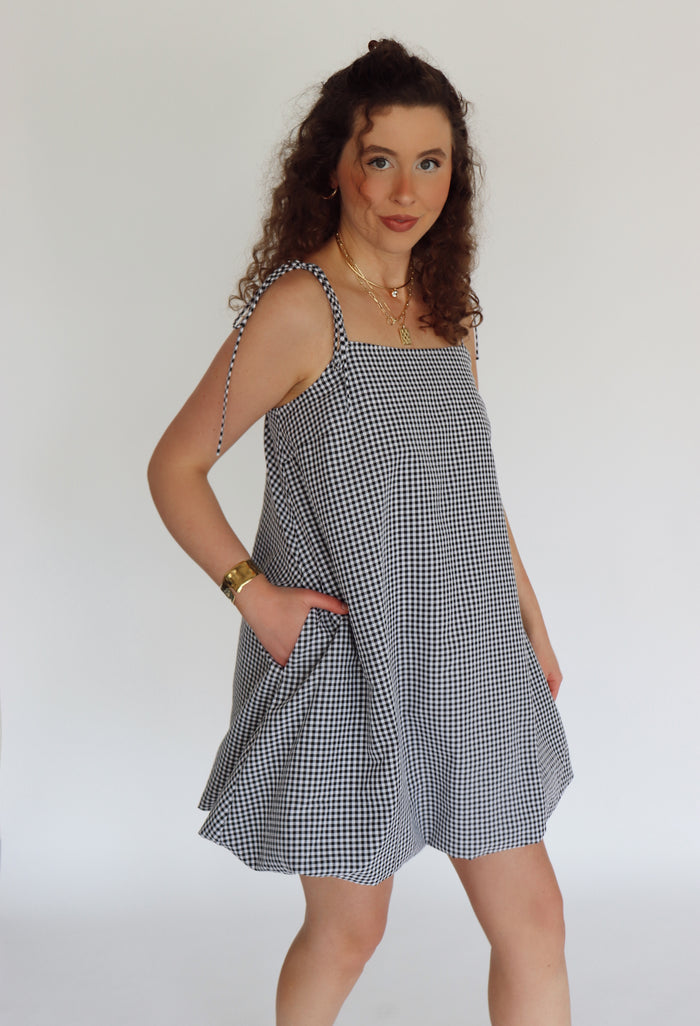 Woman wearing a black and white checkered dress against a plain background