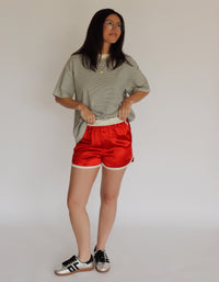 Person wearing a striped shirt and red shorts with a plain background