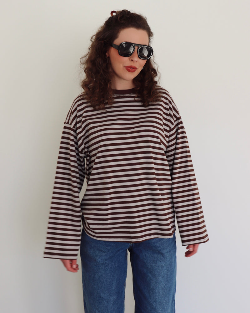 Person wearing a striped shirt and sunglasses against a plain background