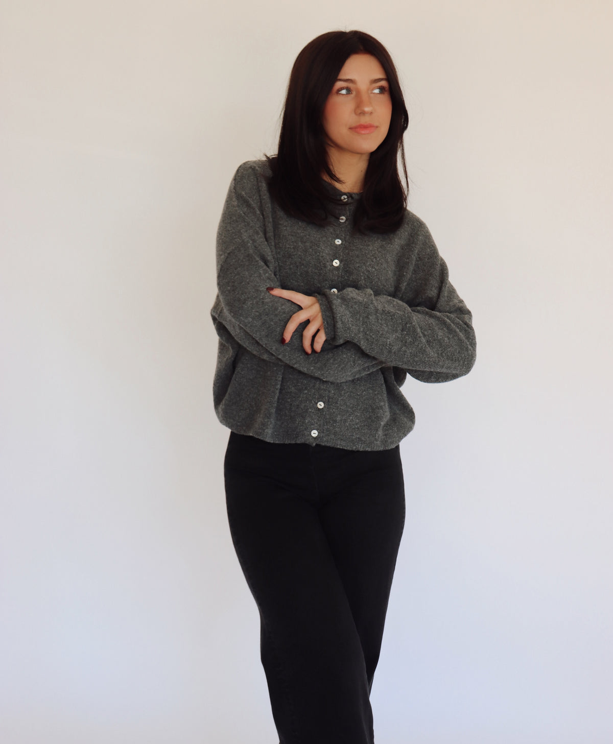 Woman wearing a gray sweater cardigan with button details against a white background