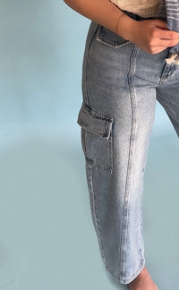 Close-up of light blue jeans with cargo pockets on a light blue background