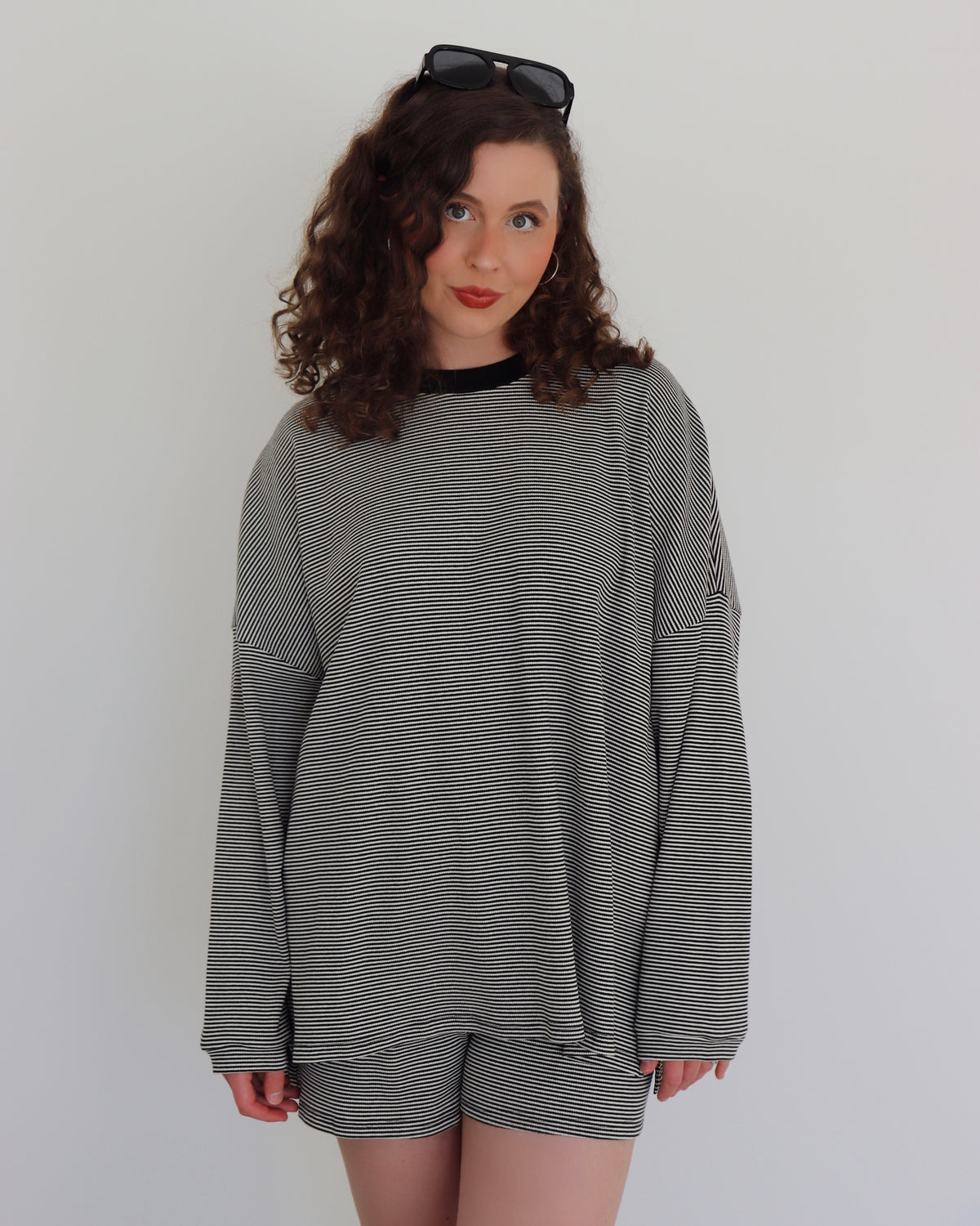 Woman wearing a black striped top and shorts against a white background