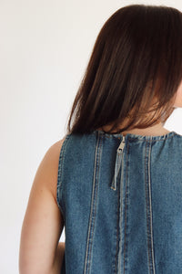 Woman wearing a denim dress against a plain background