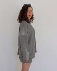 Woman wearing a black oversized top and shorts  against a plain background