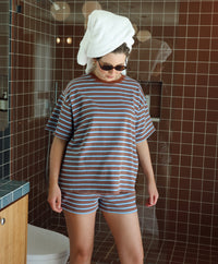 Person wearing a striped outfit with a towel on their head in a bathroom.