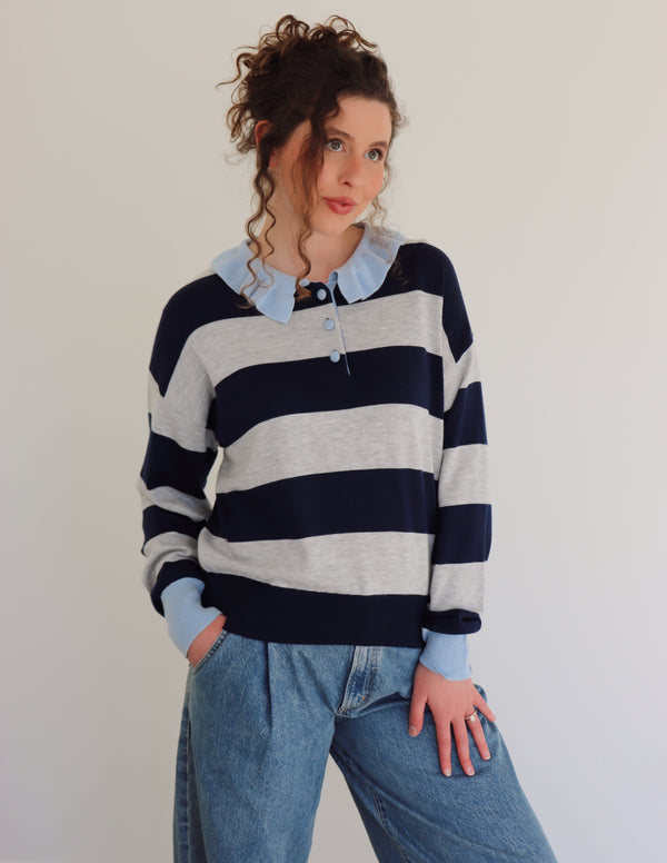 Woman wearing a striped sweater and jeans against a plain background