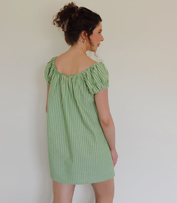 Woman wearing striped green dress against a white wall