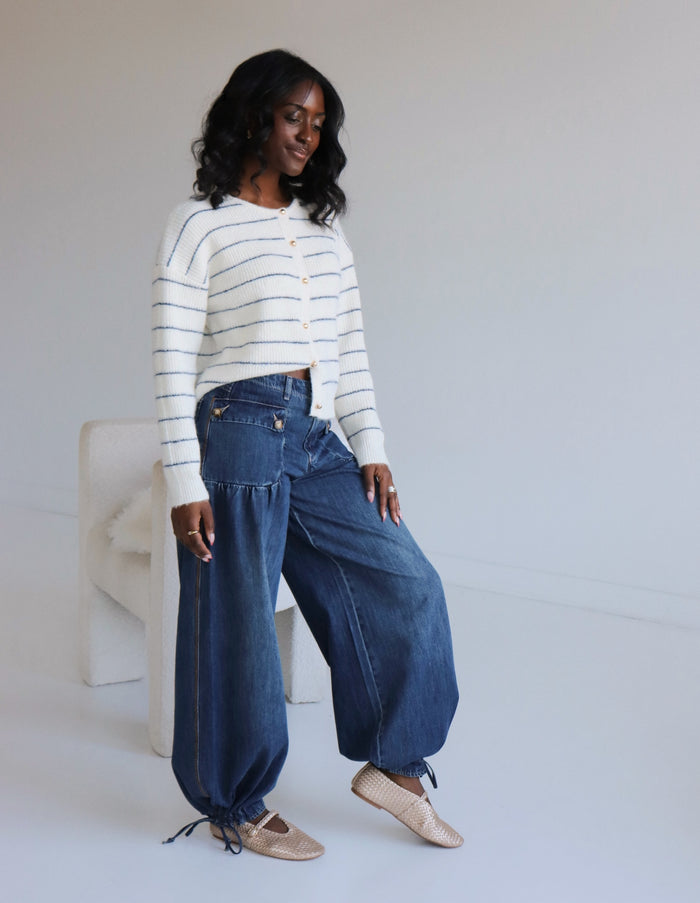 Woman wearing a striped sweater and blue jeans against a white background