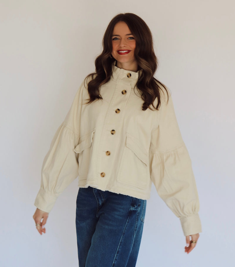 Woman wearing a beige jacket with buttons against a plain background
