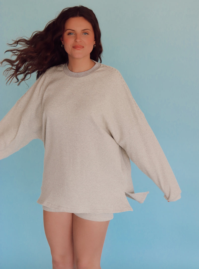 Person wearing light gray striped lounge set in front of a blue wall.