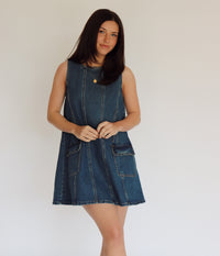 Woman wearing a denim dress against a plain background